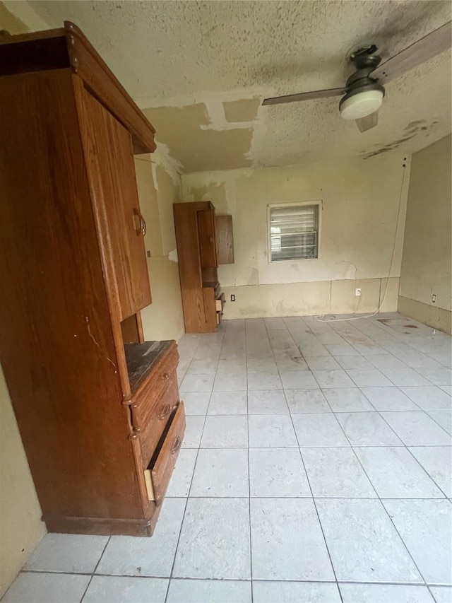 interior space featuring ceiling fan, light tile patterned floors, and a textured ceiling