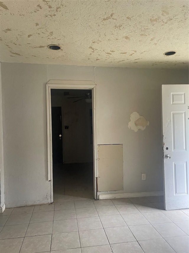 empty room with light tile patterned floors and a textured ceiling