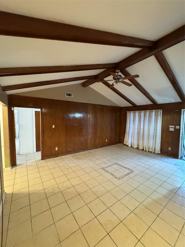 empty room featuring vaulted ceiling with beams, wood walls, ceiling fan, and light tile patterned flooring