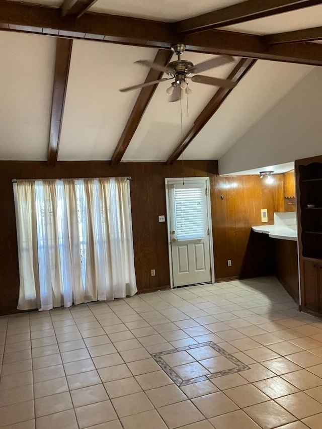 unfurnished living room featuring wooden walls, ceiling fan, a healthy amount of sunlight, and light tile patterned floors