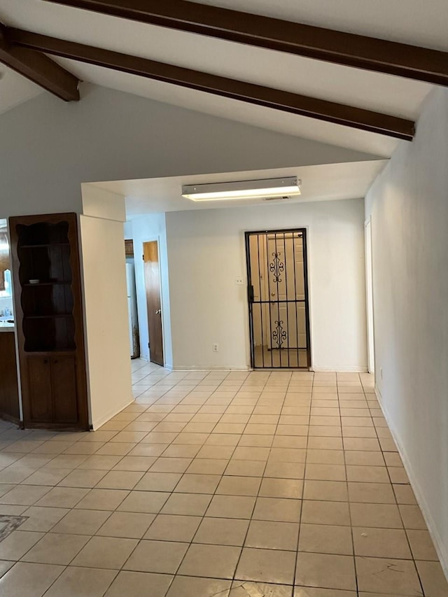 empty room featuring light tile patterned flooring and lofted ceiling with beams