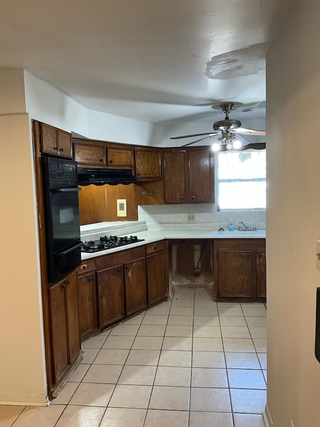 kitchen with dark brown cabinetry, gas stovetop, extractor fan, and oven