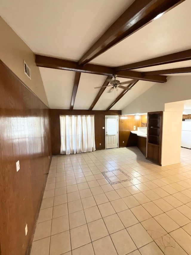 tiled spare room with lofted ceiling with beams, ceiling fan, and wood walls