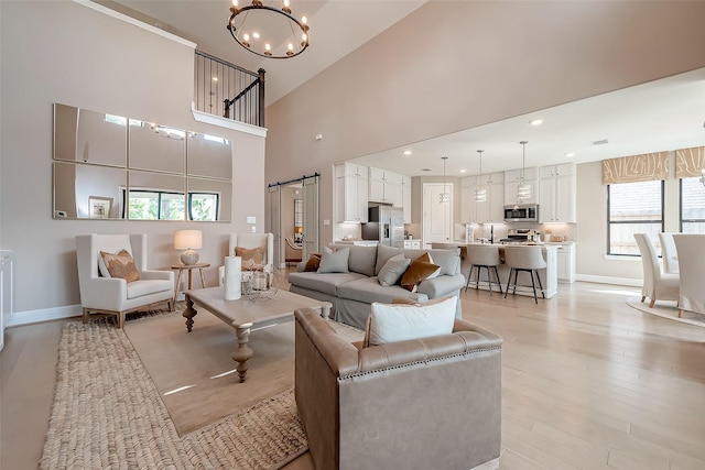 living room with light hardwood / wood-style floors, high vaulted ceiling, and a chandelier