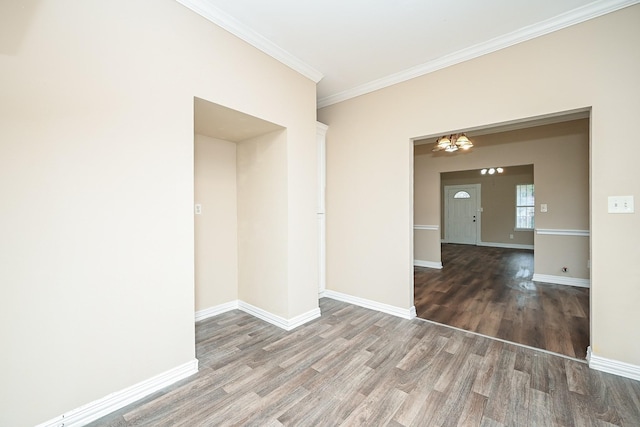 unfurnished room featuring crown molding, dark wood-type flooring, and an inviting chandelier