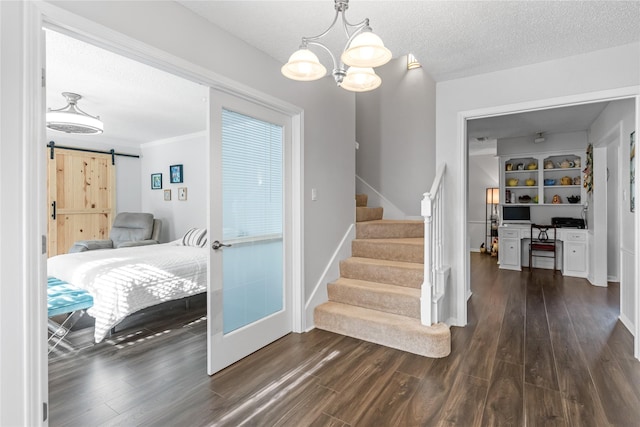 stairs with hardwood / wood-style floors, a notable chandelier, a barn door, and a textured ceiling