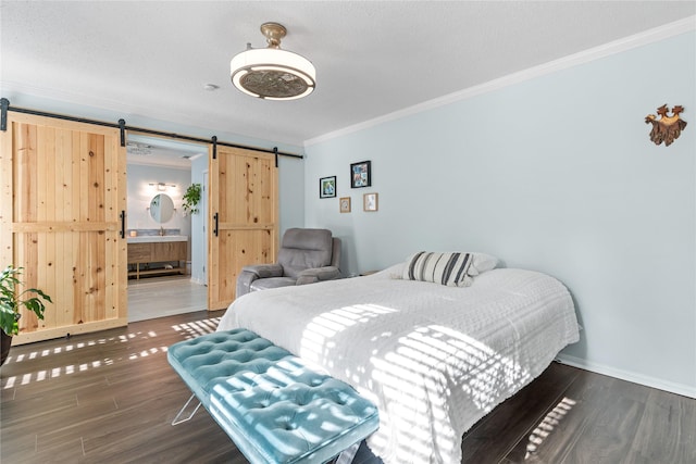 bedroom featuring a barn door, ornamental molding, dark wood-type flooring, and ensuite bath