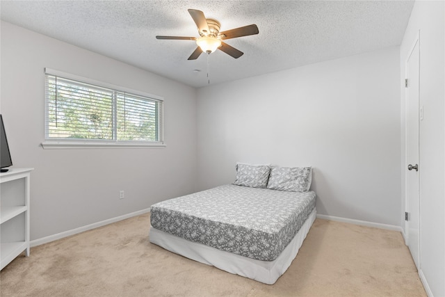 bedroom featuring ceiling fan, light colored carpet, and a textured ceiling