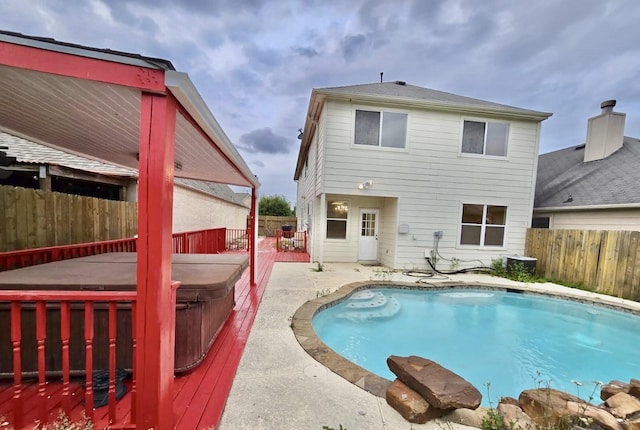 rear view of house with a pool with hot tub