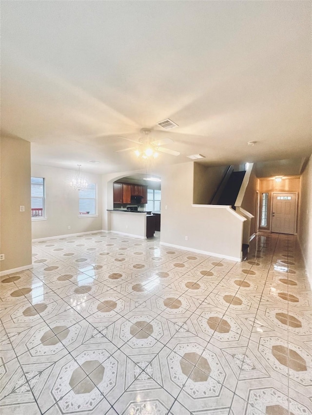 unfurnished living room featuring ceiling fan with notable chandelier