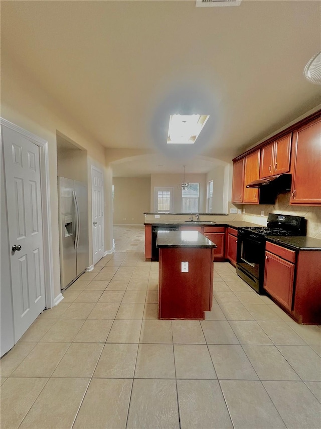 kitchen featuring black appliances, sink, a skylight, light tile patterned flooring, and kitchen peninsula