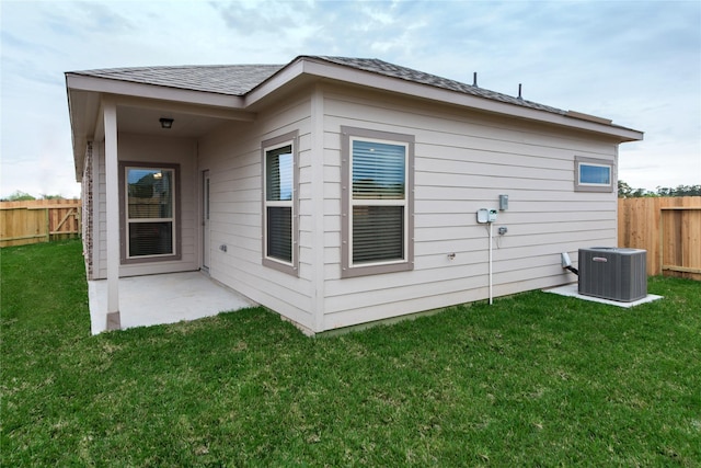 back of property with central air condition unit, a patio area, and a yard