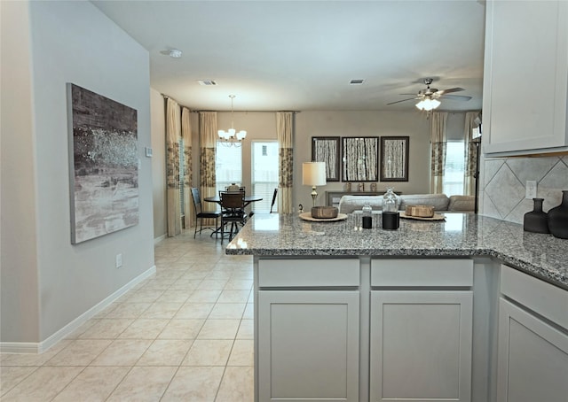 kitchen featuring light tile patterned floors, ceiling fan with notable chandelier, decorative light fixtures, and stone countertops