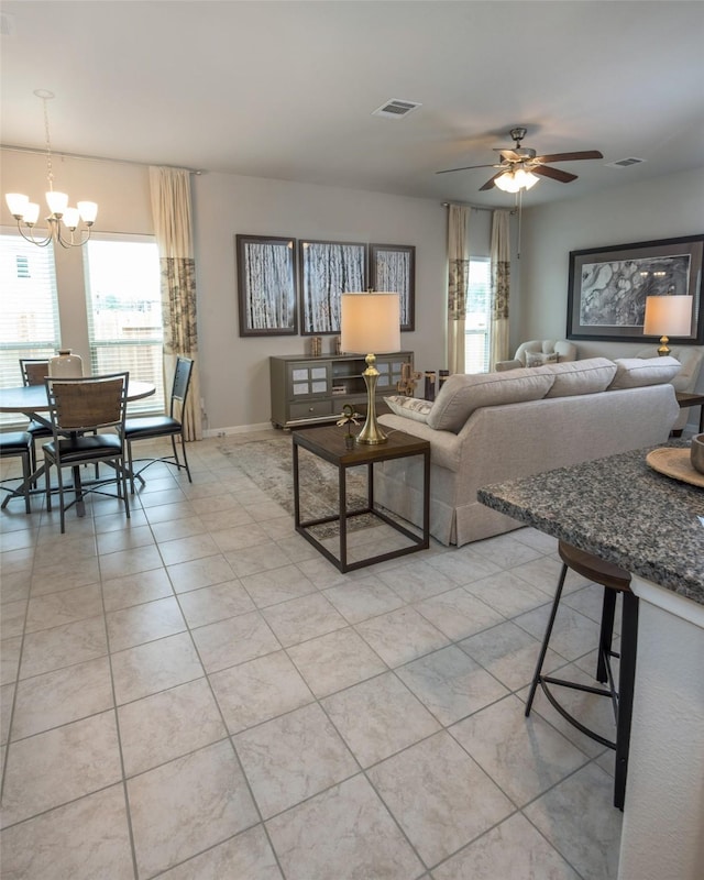 living room featuring ceiling fan with notable chandelier and light tile patterned flooring