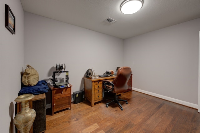 office space with light wood-type flooring and a textured ceiling