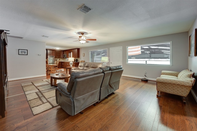 living room with ceiling fan, dark hardwood / wood-style flooring, and a textured ceiling