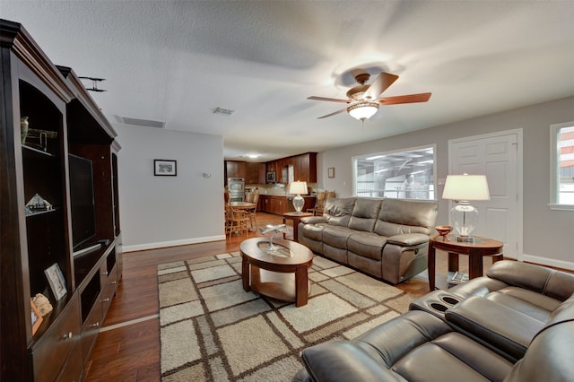 living room with ceiling fan, dark hardwood / wood-style flooring, and a textured ceiling