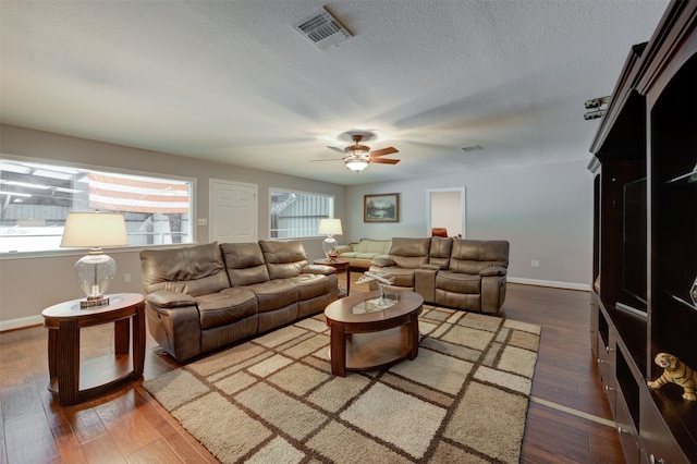 living room with dark hardwood / wood-style floors, ceiling fan, and a textured ceiling