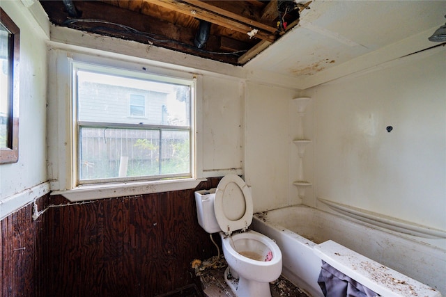 bathroom with a tub to relax in and toilet