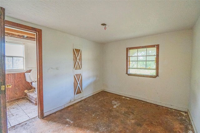 empty room with a textured ceiling and a wealth of natural light