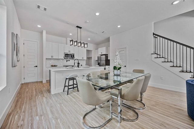 dining area with light wood-type flooring and sink