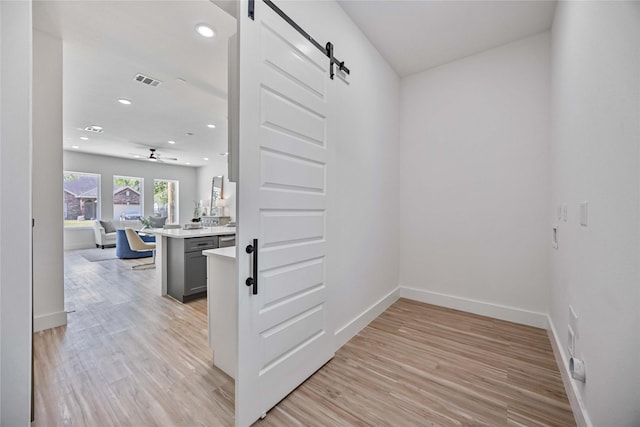 corridor featuring a barn door and light hardwood / wood-style floors