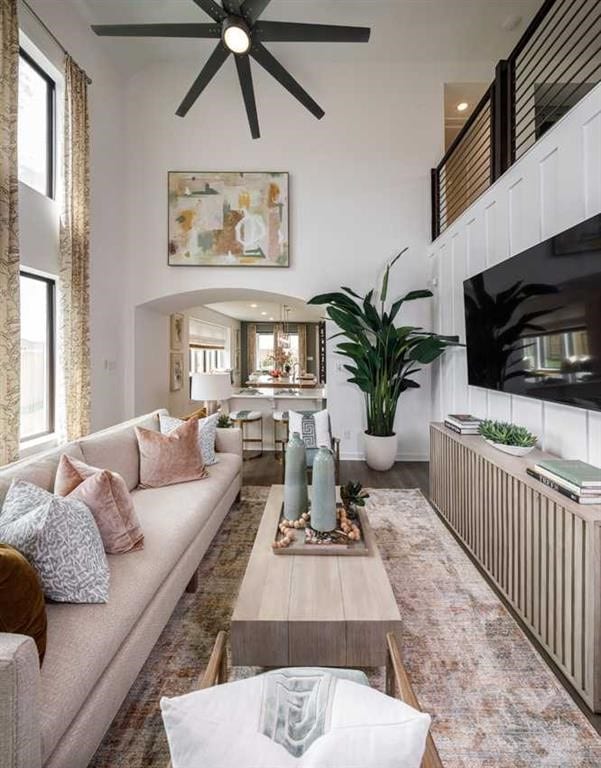 living room featuring ceiling fan, a towering ceiling, and dark wood-type flooring