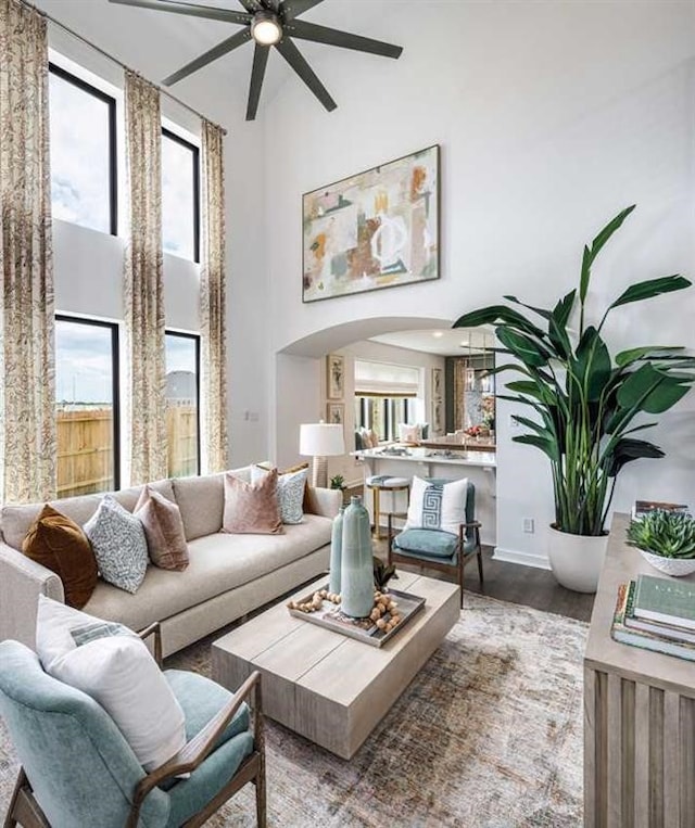 living room featuring ceiling fan, wood-type flooring, and a high ceiling