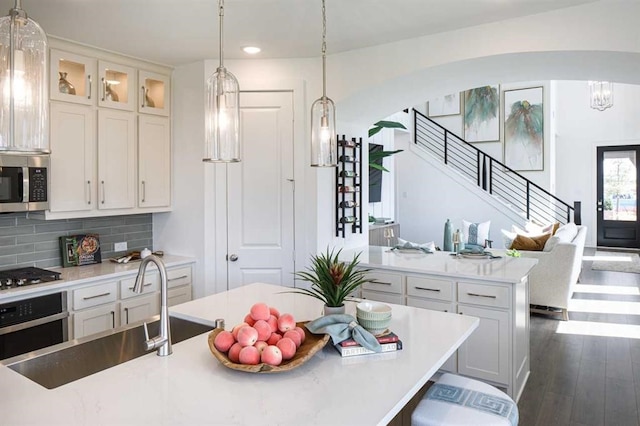 kitchen with white cabinets, sink, dark hardwood / wood-style floors, appliances with stainless steel finishes, and a kitchen island