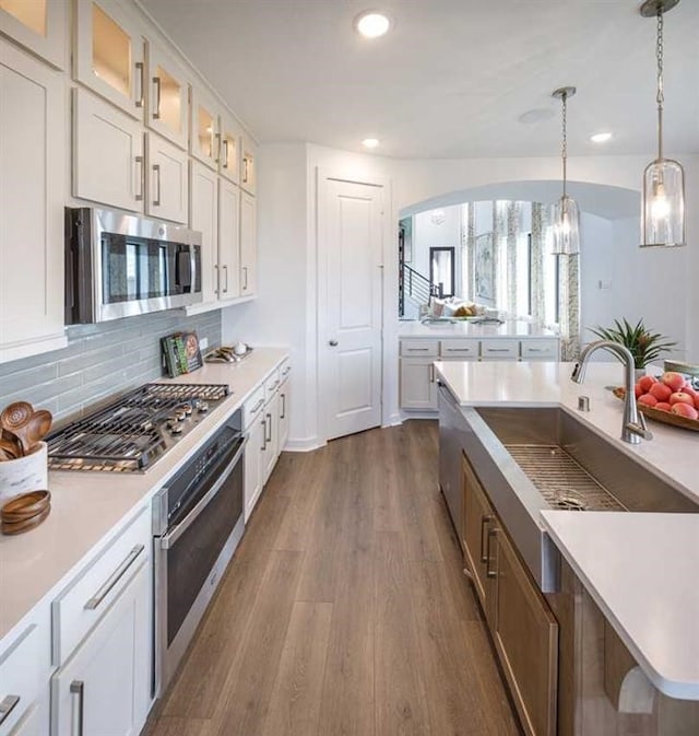 kitchen with sink, stainless steel appliances, dark hardwood / wood-style floors, pendant lighting, and white cabinets