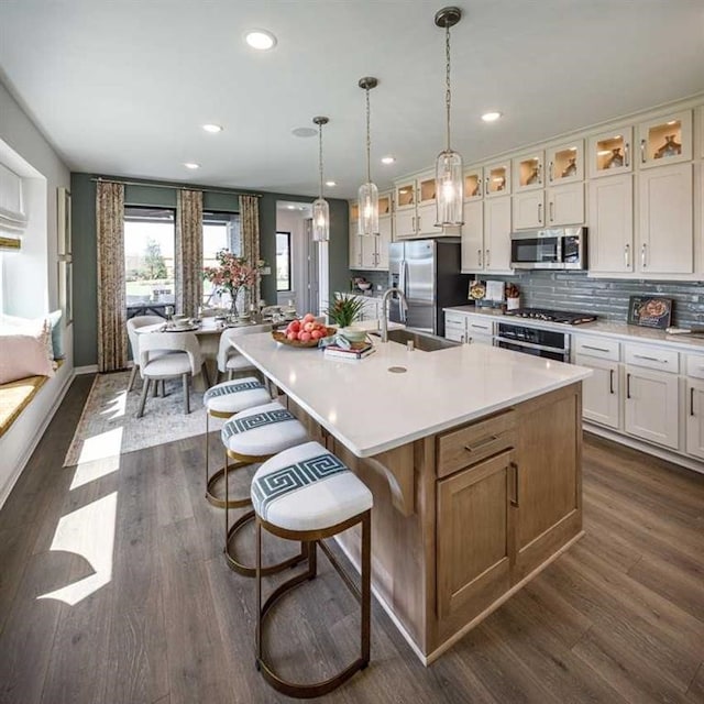 kitchen featuring sink, hanging light fixtures, dark wood-type flooring, a spacious island, and appliances with stainless steel finishes