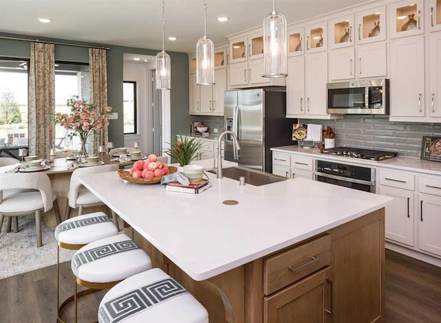 kitchen with a breakfast bar, appliances with stainless steel finishes, a kitchen island with sink, and sink