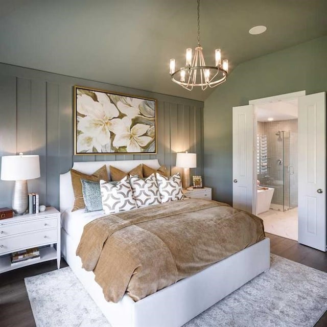 bedroom featuring ensuite bathroom, hardwood / wood-style floors, lofted ceiling, and a notable chandelier