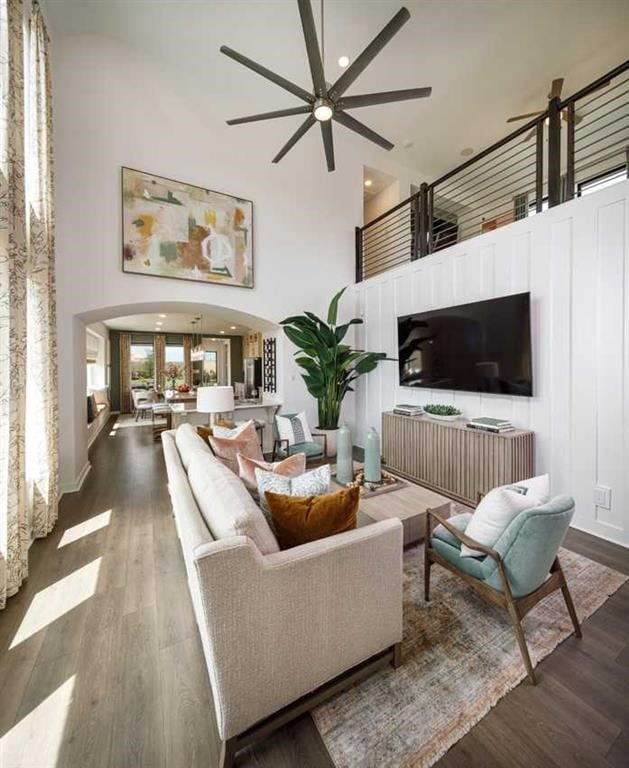 living room featuring dark hardwood / wood-style floors, ceiling fan, and a high ceiling