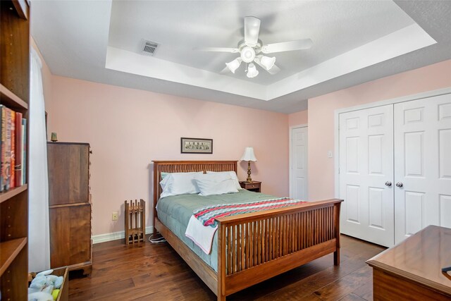 bedroom featuring ceiling fan, dark hardwood / wood-style floors, and a raised ceiling