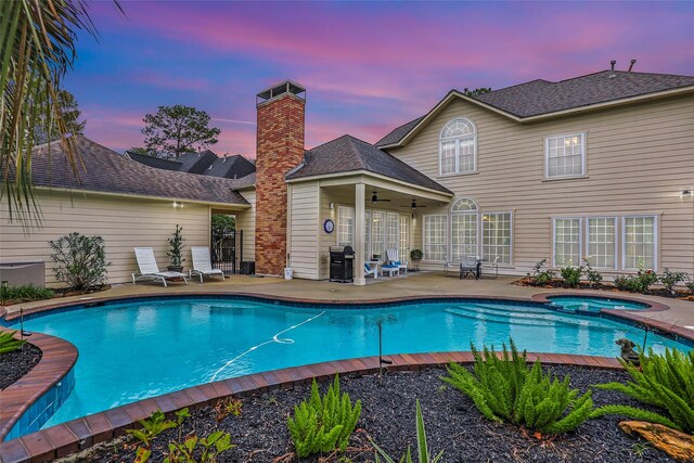 pool at dusk featuring an in ground hot tub, a patio, area for grilling, and ceiling fan