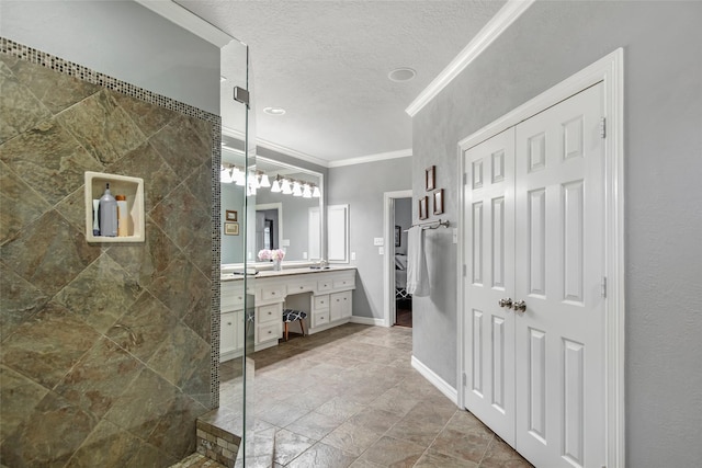 bathroom with vanity, a tile shower, ornamental molding, and a textured ceiling