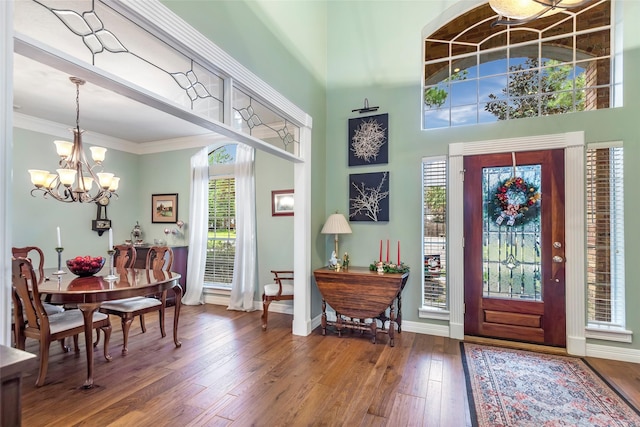 foyer entrance featuring a chandelier, crown molding, a towering ceiling, and wood-type flooring