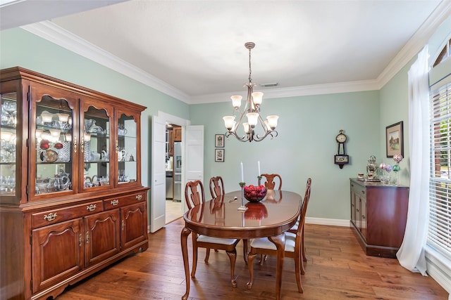 dining area featuring dark hardwood / wood-style flooring, ornamental molding, and a notable chandelier