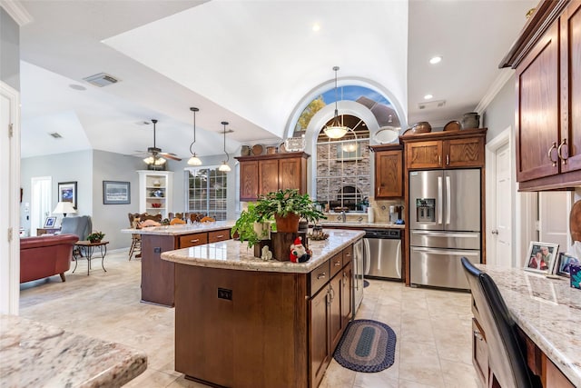 kitchen featuring hanging light fixtures, vaulted ceiling, ceiling fan, appliances with stainless steel finishes, and a kitchen island