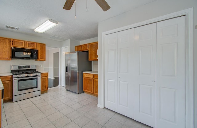 kitchen featuring a textured ceiling, ceiling fan, light tile patterned floors, and stainless steel appliances