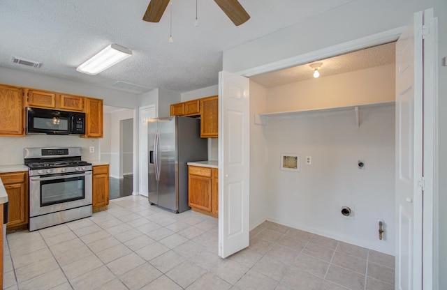 kitchen featuring ceiling fan, light tile patterned floors, a textured ceiling, and appliances with stainless steel finishes