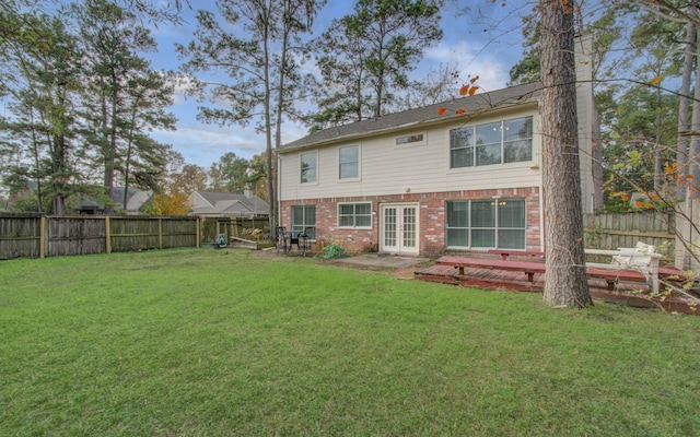 rear view of house featuring a lawn, french doors, and a deck