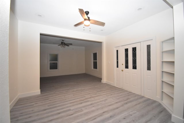 interior space featuring built in shelves, light hardwood / wood-style floors, and ceiling fan