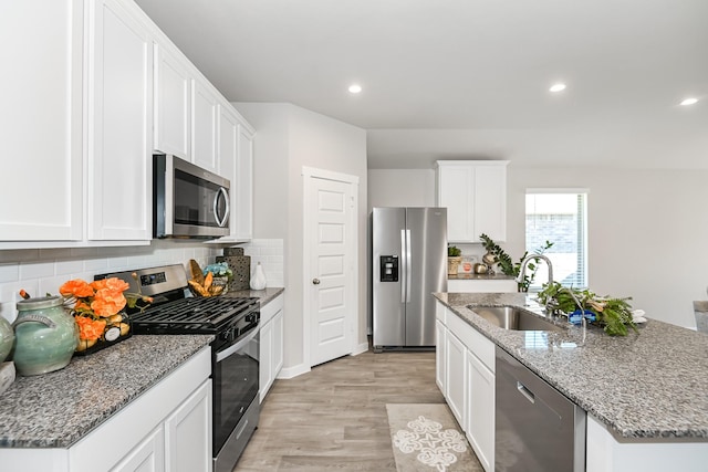 kitchen featuring a kitchen island with sink, white cabinets, sink, light hardwood / wood-style floors, and stainless steel appliances