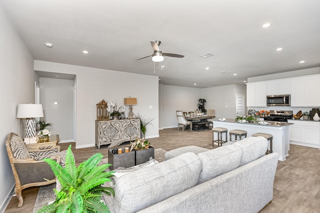 living room with light hardwood / wood-style flooring and ceiling fan