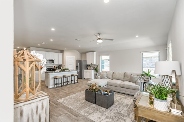 living room with plenty of natural light, ceiling fan, and light wood-type flooring