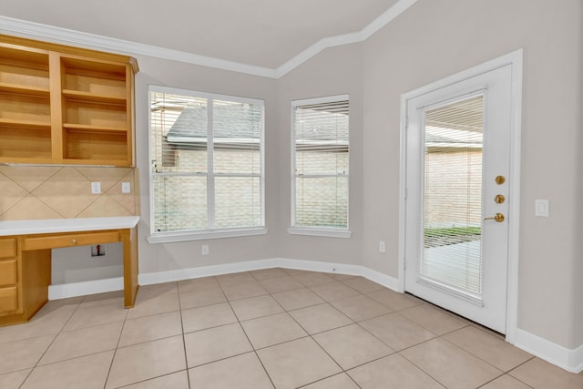 interior space with light tile patterned floors, built in desk, crown molding, and a healthy amount of sunlight