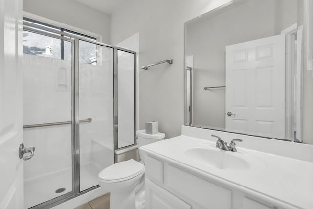 bathroom featuring tile patterned flooring, vanity, toilet, and a shower with door