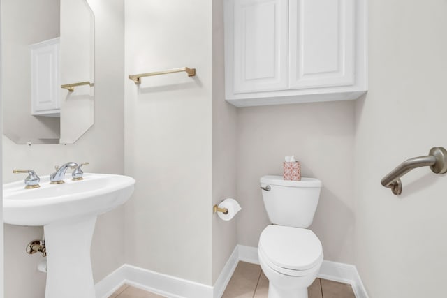 bathroom with toilet, tile patterned floors, and sink